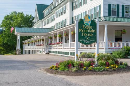 Eagle Mountain House sign in front of a large, white hotel with green accents and colorful flower beds.