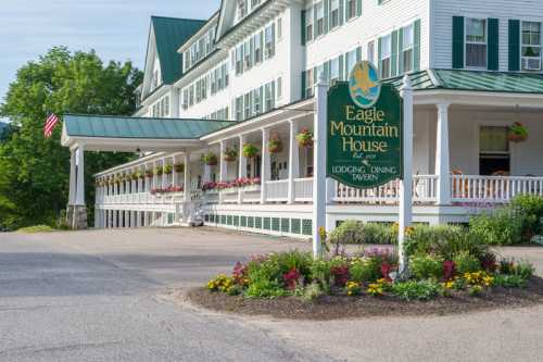 Eagle Mountain House sign in front of a large, white hotel with green accents and colorful flower beds.