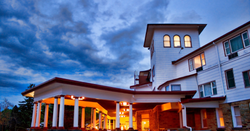 Historic building with a tower, illuminated under a dramatic sky, featuring columns and a welcoming entrance.