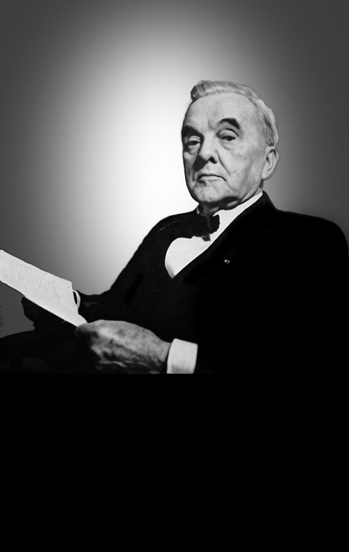 A distinguished man in formal attire, holding a document, with a serious expression against a gradient background.