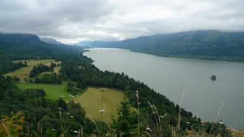 A scenic view of a river winding through lush green hills under a cloudy sky.