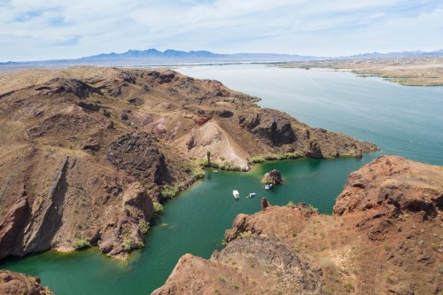 Aerial view of a winding river surrounded by rocky hills and mountains under a clear blue sky.