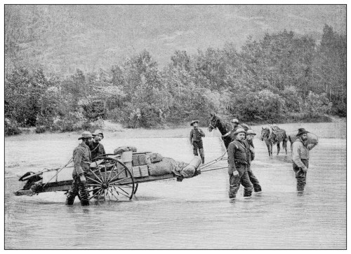 A group of men crossing a river with a cart and horses, carrying supplies in a rugged landscape.