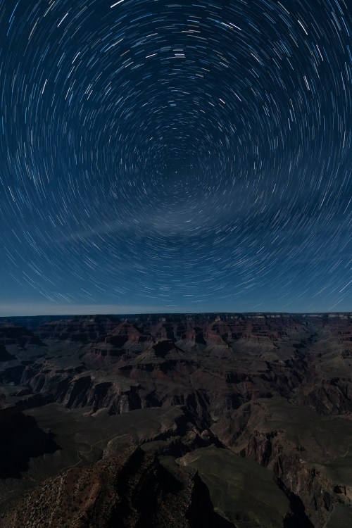 Star trails swirl above the Grand Canyon, capturing a stunning night sky over the rugged landscape.