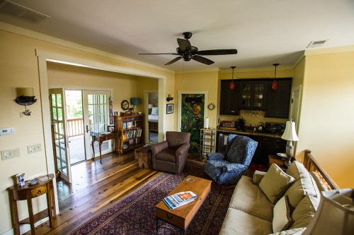 Cozy living room with a sofa, armchairs, wooden coffee table, and a view of a kitchen and outdoor deck.