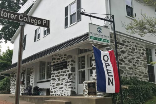 A stone building with a sign for the Appalachian Trail Visitor Center and an "Open" flag hanging outside.