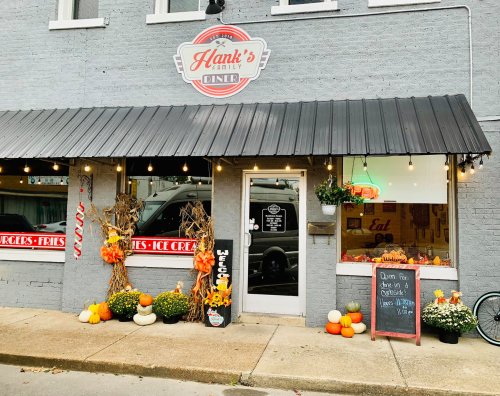 Exterior of Hank's Family Diner decorated for fall, featuring pumpkins, lights, and a welcoming sign.