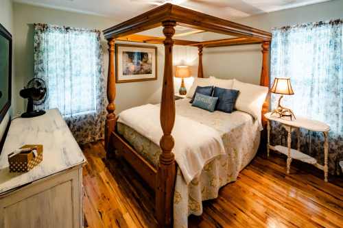 Cozy bedroom featuring a four-poster bed, wooden floors, and soft lighting from bedside lamps and windows.