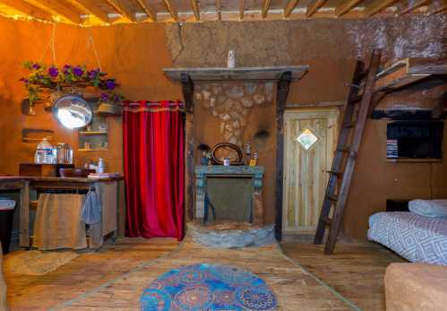 Cozy interior of a rustic room with earthy tones, a fireplace, wooden accents, and a red curtain.