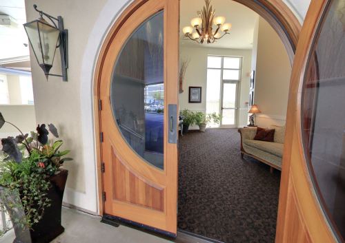 A welcoming entrance with a large wooden door, leading to a cozy lobby with plants and a sofa.
