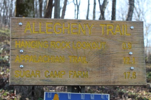 Wooden signpost indicating distances to Hanging Rock Lookout, Appalachian Trail, and Sugar Camp Farm on the Allegheny Trail.