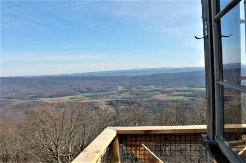 A scenic view from a window overlooking rolling hills and valleys under a clear blue sky.