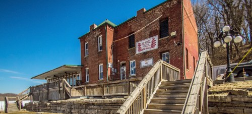 Historic brick building with a wooden staircase, set against a clear blue sky.