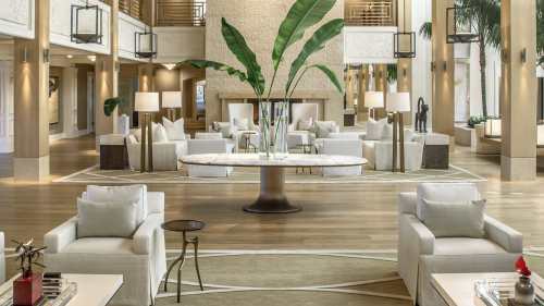 A spacious hotel lobby with modern furniture, large plants, and warm lighting, creating a welcoming atmosphere.