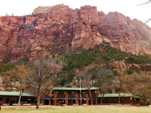 A large rock formation towers over a building surrounded by trees in a scenic landscape.