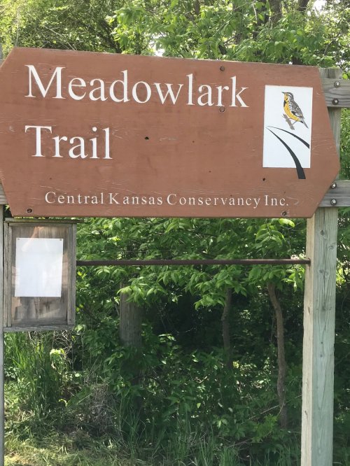 Wooden sign for Meadowlark Trail, featuring a bird illustration and text about Central Kansas Conservancy Inc.