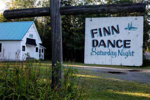 Sign for "Finn Dance" with a white building and greenery in the background, indicating Saturday night events.