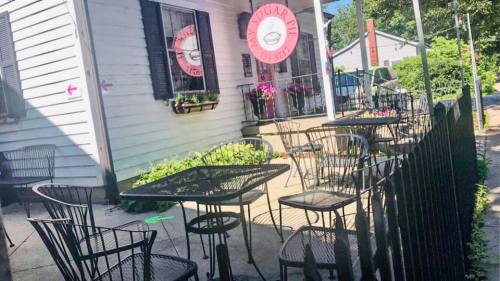 Outdoor seating area of a quaint café with black metal tables and chairs, featuring a sign that reads "Sugar Pie."