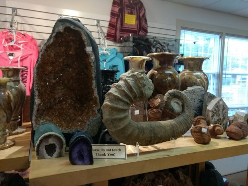Display of decorative stone and pottery items, including a large geode and various vases, in a retail setting.