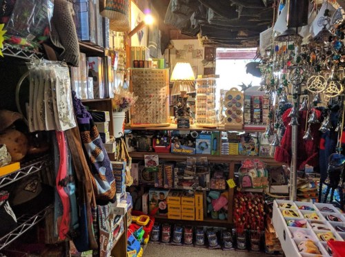 A cozy shop filled with colorful crafts, trinkets, and various items displayed on shelves and tables.