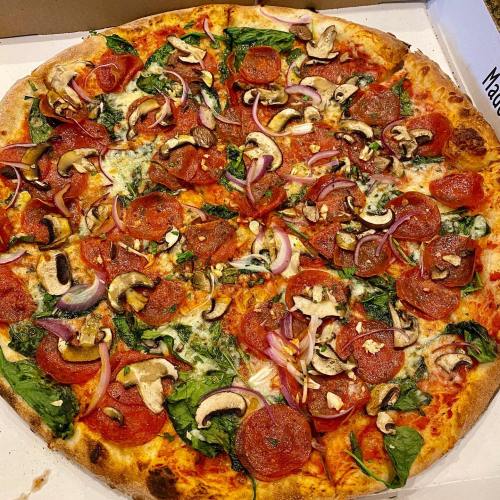 A large pizza topped with pepperoni, spinach, mushrooms, and red onions in a pizza box.