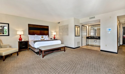 A spacious hotel room featuring a king bed, seating area, and a bathroom with modern amenities.