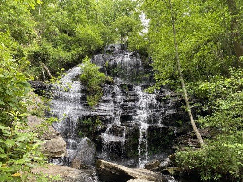 A serene waterfall cascading over rocky terrain, surrounded by lush green trees and foliage.