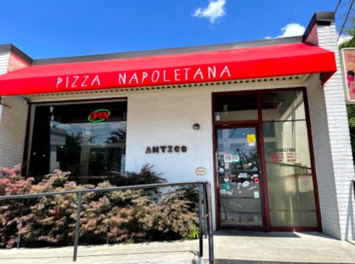 Exterior of Antico Pizza Napoletana with a red awning, "OPEN" sign, and a clear blue sky above.