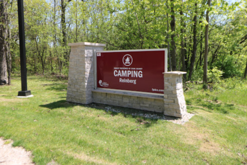 Sign for Reinberg Camping in Cook County, surrounded by greenery and grass.
