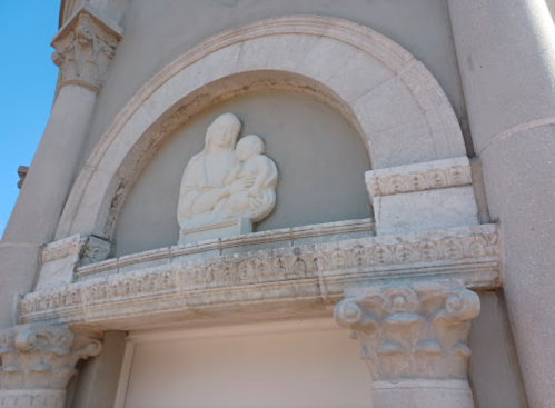 Relief sculpture of a mother and child above an arch, framed by ornate stone columns.