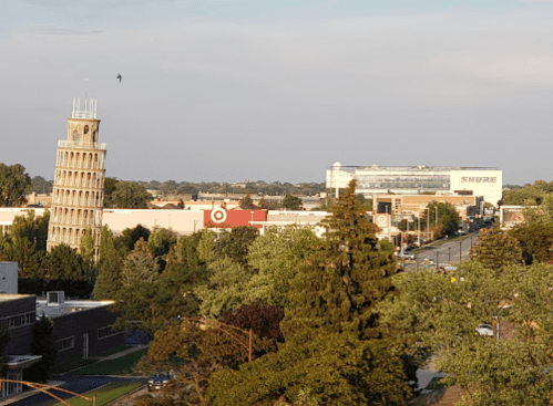 A leaning tower structure near a Target store, with trees and buildings in the background under a clear sky.