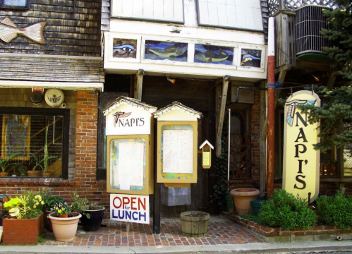 Exterior of Napi's restaurant with a sign reading "Open for Lunch" and potted plants by the entrance.