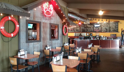 Cozy restaurant interior with wooden tables, a rustic crab shack decor, and a chalkboard menu in the background.