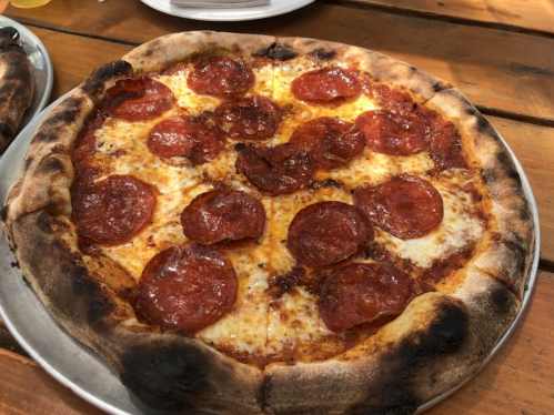 A freshly baked pepperoni pizza with a golden crust and melted cheese, served on a metal tray.