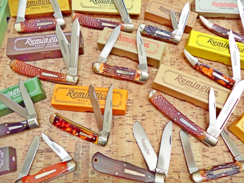 A collection of vintage Remington pocket knives displayed with their original boxes on a cork surface.