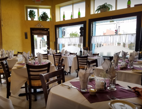 A cozy restaurant interior with tables set for dining, featuring white tablecloths and decorative napkins.