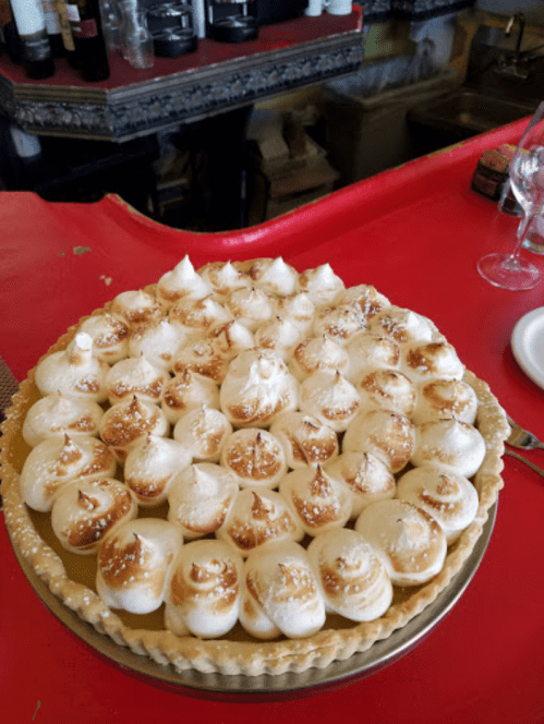 A beautifully decorated pie topped with swirls of toasted meringue, sitting on a red countertop.