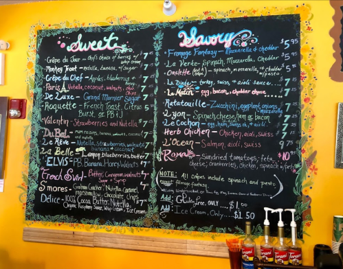 Chalkboard menu featuring sweet and savory dishes with prices, colorful design, and playful descriptions.