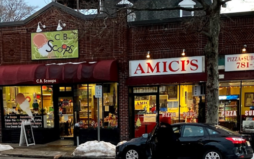 A storefront featuring "C.B. Scoops" ice cream shop and "Amici's" pizza restaurant, with snow on the ground.