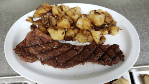 A plate featuring a grilled steak alongside crispy, golden-brown roasted potatoes.
