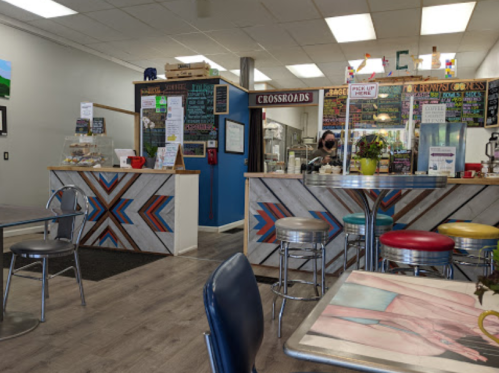 A cozy café interior with colorful decor, a service counter, and tables. Bright lighting and a welcoming atmosphere.