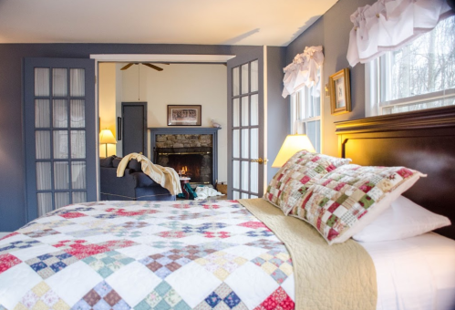 Cozy bedroom with a quilted bedspread, fireplace, and soft lighting, creating a warm and inviting atmosphere.