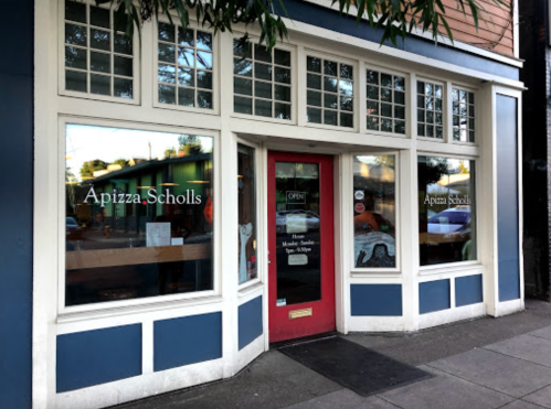 Exterior view of Apizza Scholls, featuring large windows and a red door, with "Open" sign visible.