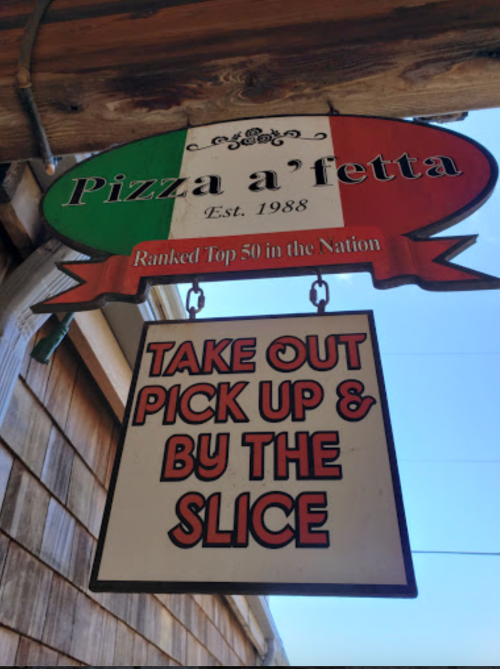 Sign for "Pizza a Fetta," established in 1988, offering takeout and slices, ranked in the top 50 in the nation.