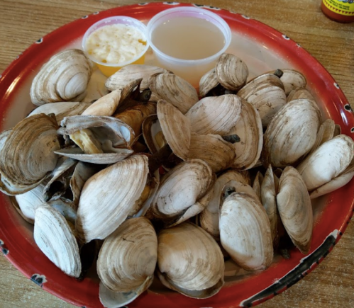 A plate of fresh clams with two dipping sauces on the side.