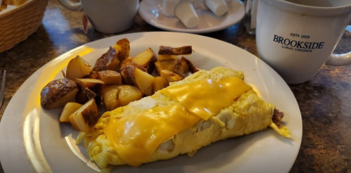 A plate with a cheese omelet, golden potatoes, and a coffee mug on a table.