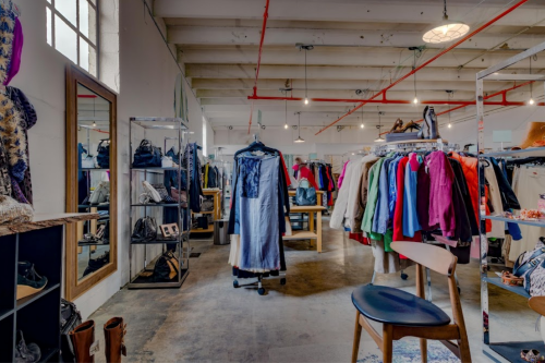 A stylish clothing store interior with racks of colorful garments, mirrors, and modern furniture.