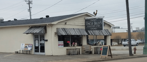 Exterior of Uncle Billy's Downtown Bakery, featuring a rustic sign, flower displays, and a rooster on the roof.