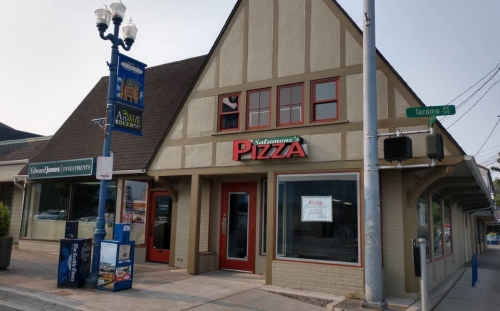 A pizza restaurant with a sign reading "Salvatore's Pizza," located on a street corner with nearby signage.