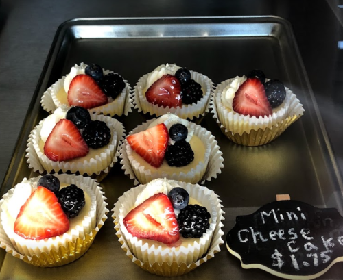 A tray of mini cheesecakes topped with strawberries, blueberries, and blackberries, with a price tag of $1.95.